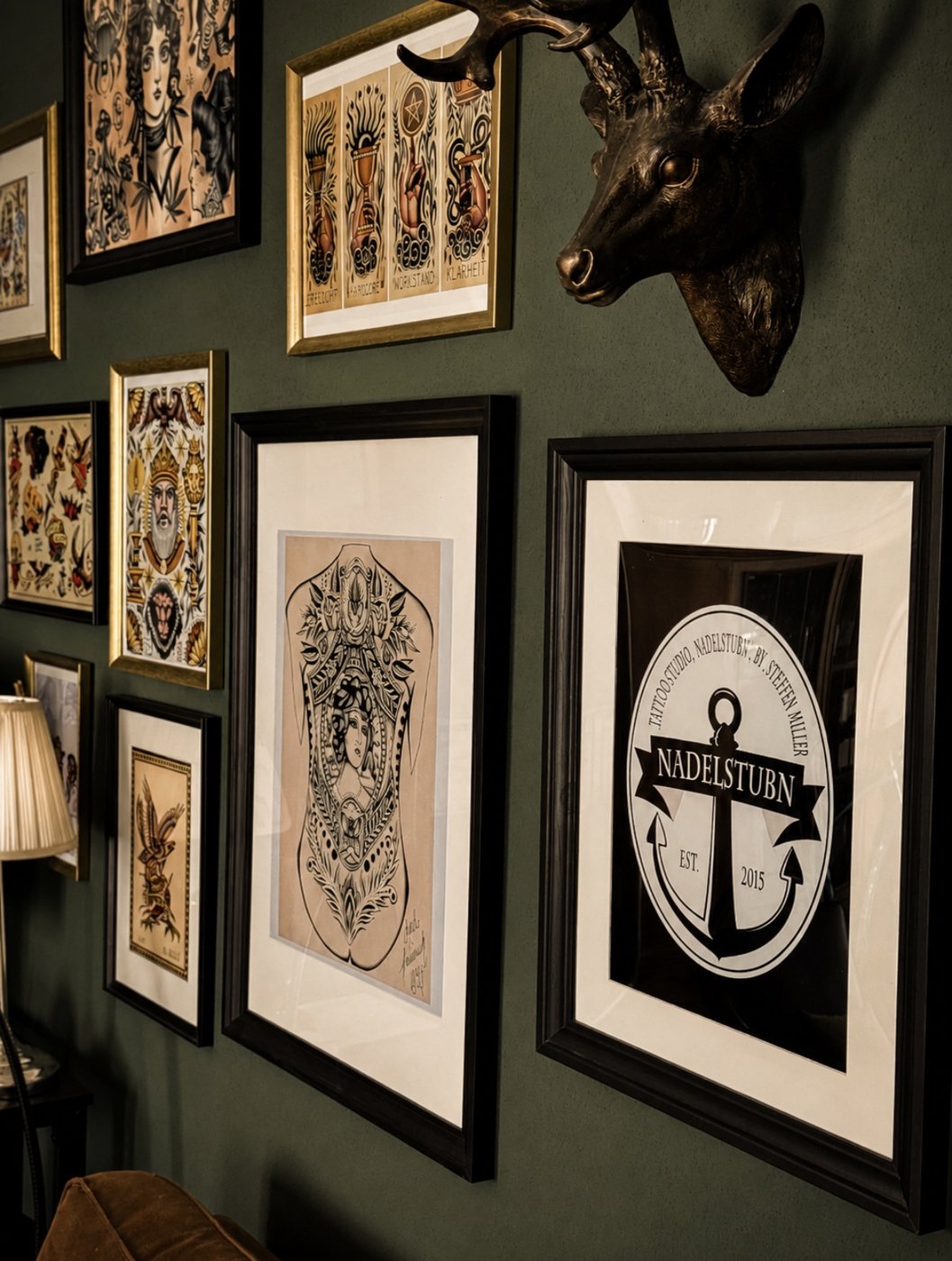 Nadelstub'n Studio Wand mit gerahmten Tattoo-Motiven und Logo
